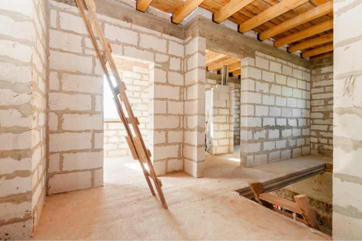 Baustelle der Erweiterung Wohngebäude Innenraum im Gange zu neuem Haus. Leeres Zimmer mit weißer Ziegelmauer, Holzleiter und Eingang.